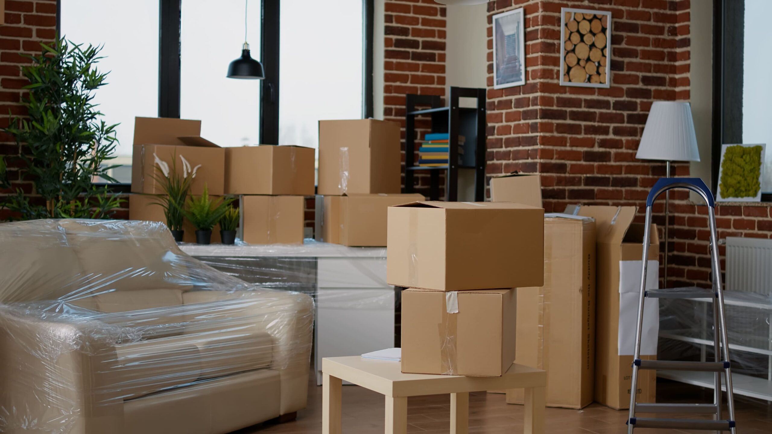 Wohnzimmer mit Kartons und verpackten Möbeln